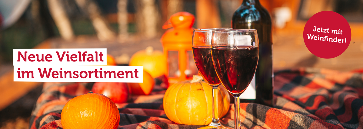 KI generiert: Weingläser und Kürbisse auf Decke, Text: "Neue Vielfalt im Weinsortiment. Jetzt mit Weinfinder!"