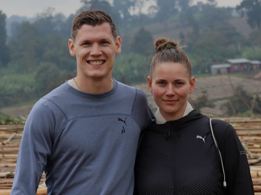 KI generiert: Ein Mann und eine Frau lächeln vor einer ländlichen Landschaft in die Kamera.