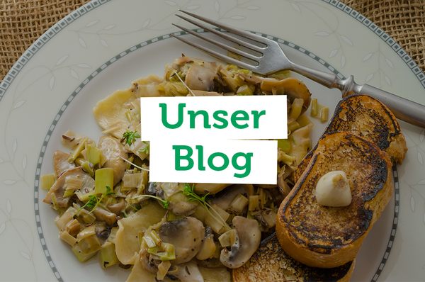 Ein weißer Teller mit einer Portion Pasta mit Pilzen und dazu geröstetes Brot