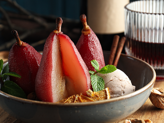 KI generiert: Gekochte rote Birnen mit Vanilleeis, Minze, Zimtstangen und einer getrockneten Orangenscheibe in einer Schale.