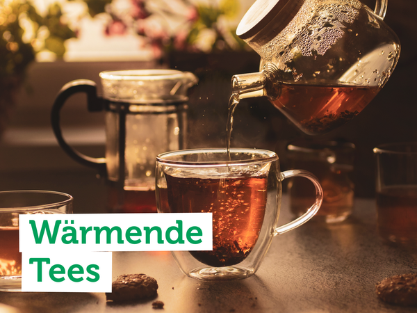 KI generiert: Ein Glas Tee wird eingegossen, umgeben von Teetassen. Text: "Wärmende Tees".