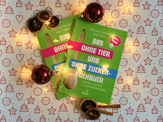 KI generiert: Kochbuch mit Lichterkette, Weihnachtskugeln und getrockneten Orangen. Text: "DAS OHNE TIER UND OHNE ZUCKER-KOCHBUCH".