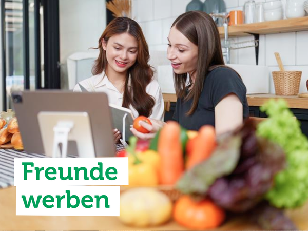 Zwei Frauen in der Küche mit Gemüse und Tablet. Text: "Freunde werben".