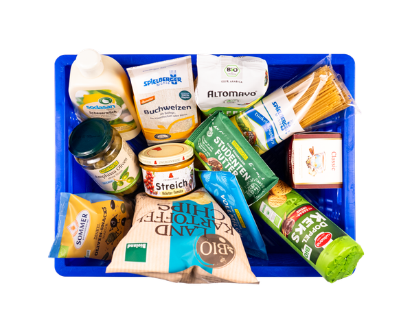 KI generiert: Eine blaue Kiste voller Bio-Lebensmittel, darunter Buchweizen, Nudeln, Chips und vegane Aufstriche.