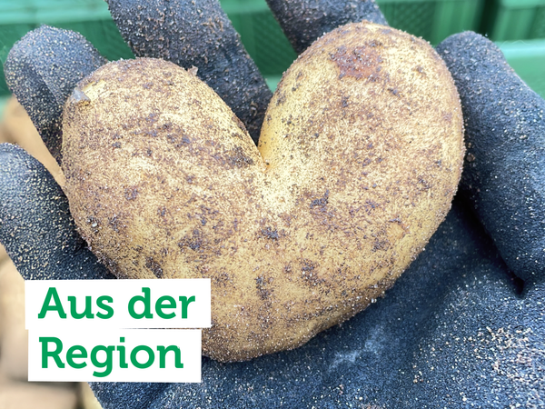 Eine herzförmige Kartoffel in einer Hand. Text: "Aus der Region".