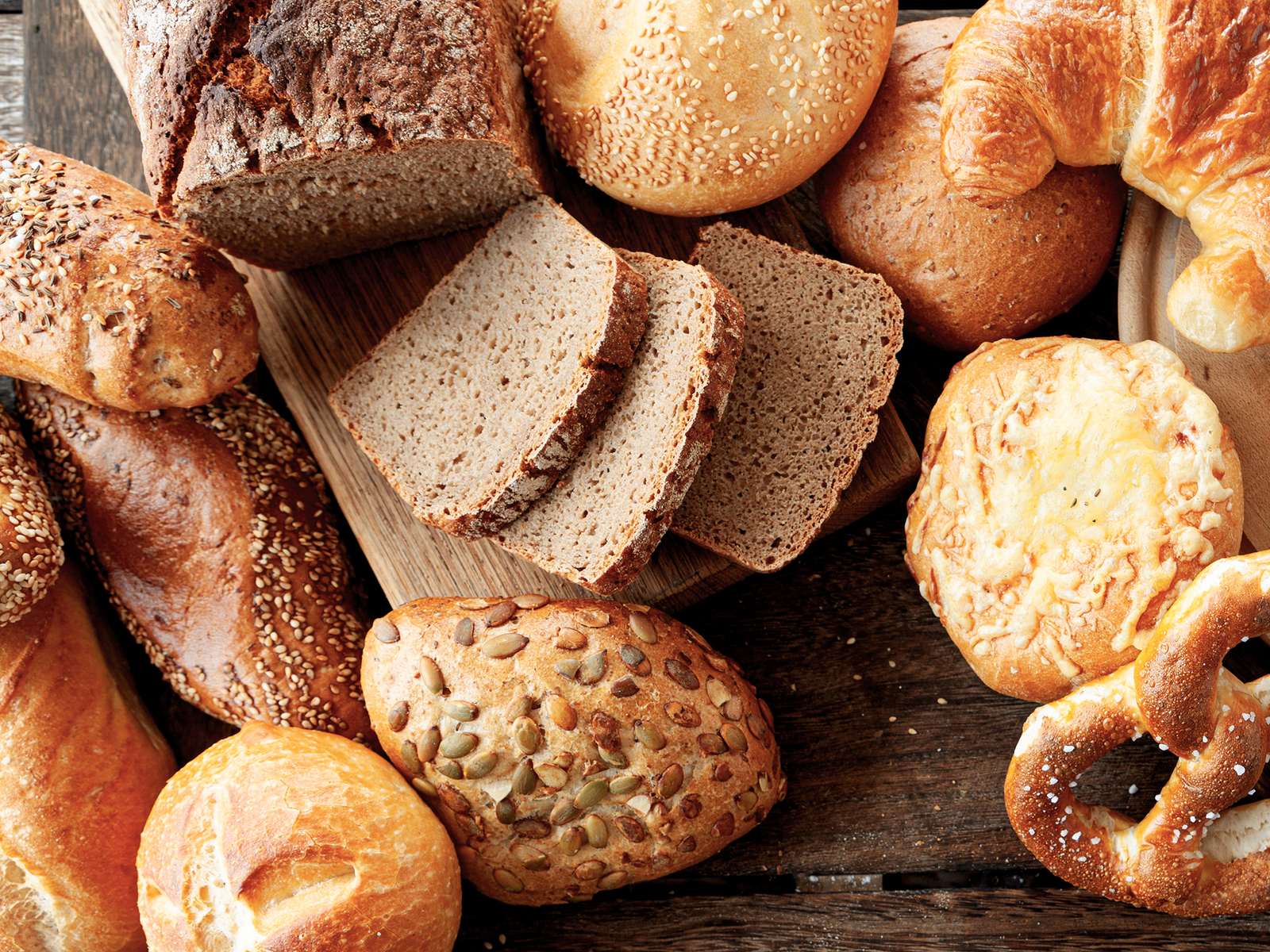 Vogelperspektive auf eine Holzfläche auf der verschiedene Brot- und Brötchensorten liegen