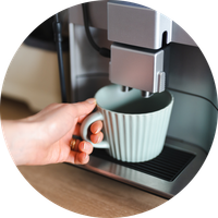 KI generiert: Eine Hand hält eine Tasse unter die Düse einer Kaffeemaschine.