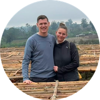 KI generiert: Ein Paar steht auf Holzbalken, im Hintergrund sind Bäume und Felder zu sehen.