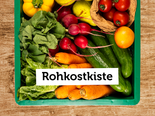 KI generiert: Eine Kiste voller frischem Gemüse und Obst. Text: "Rohkostkiste".