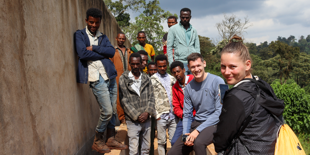KI generiert: Eine Gruppe von Menschen posiert draußen für ein Foto vor einer Wand mit Bäumen im Hintergrund.